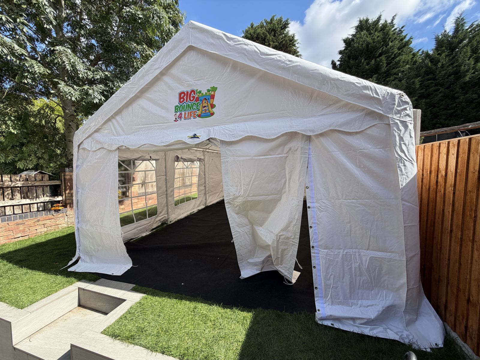 Front of the white marquee in sunshine, door panels tied back over black flooring
