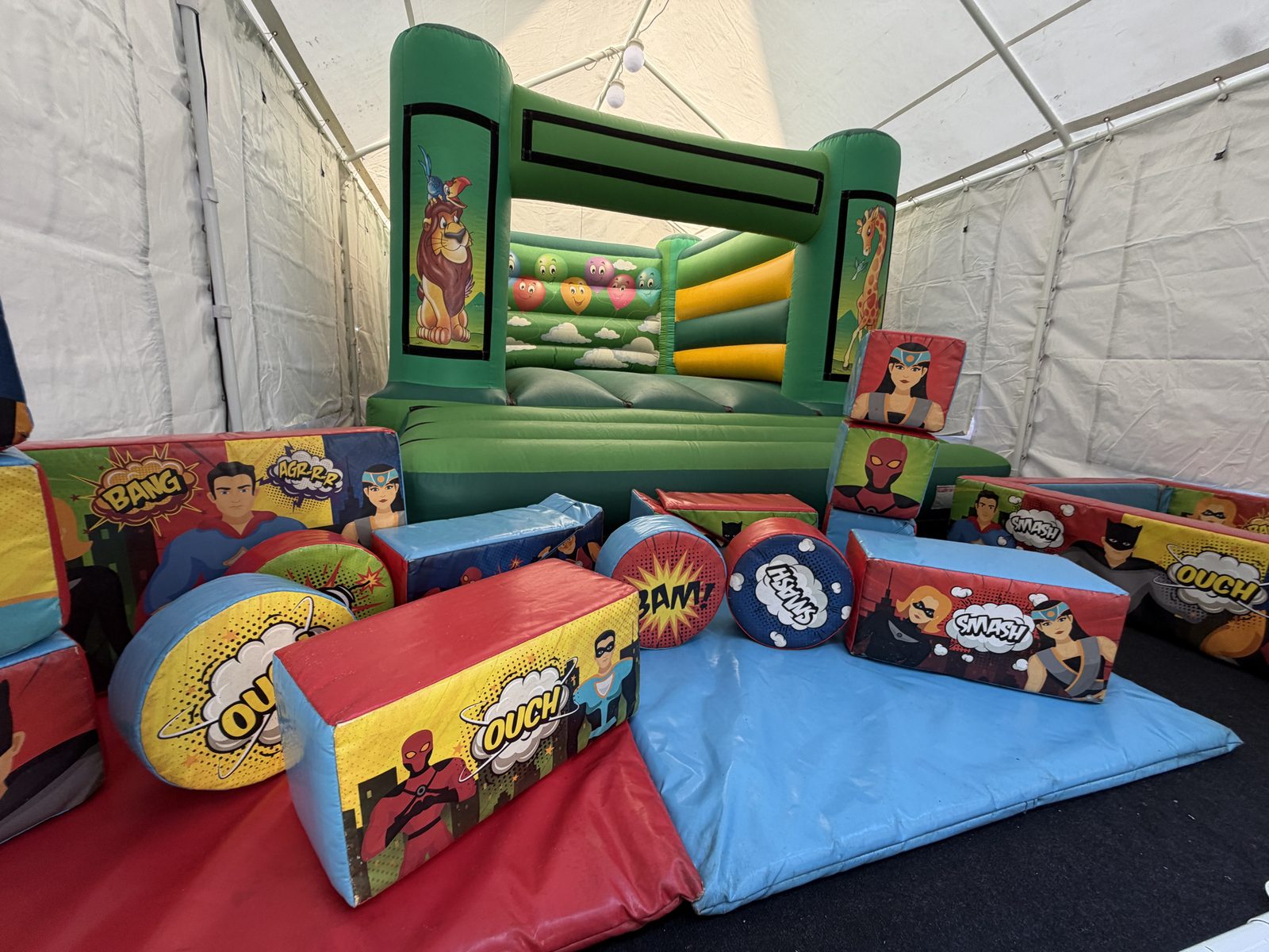 Bouncy castle and soft play blocks with crash mats laid out inside the marquee