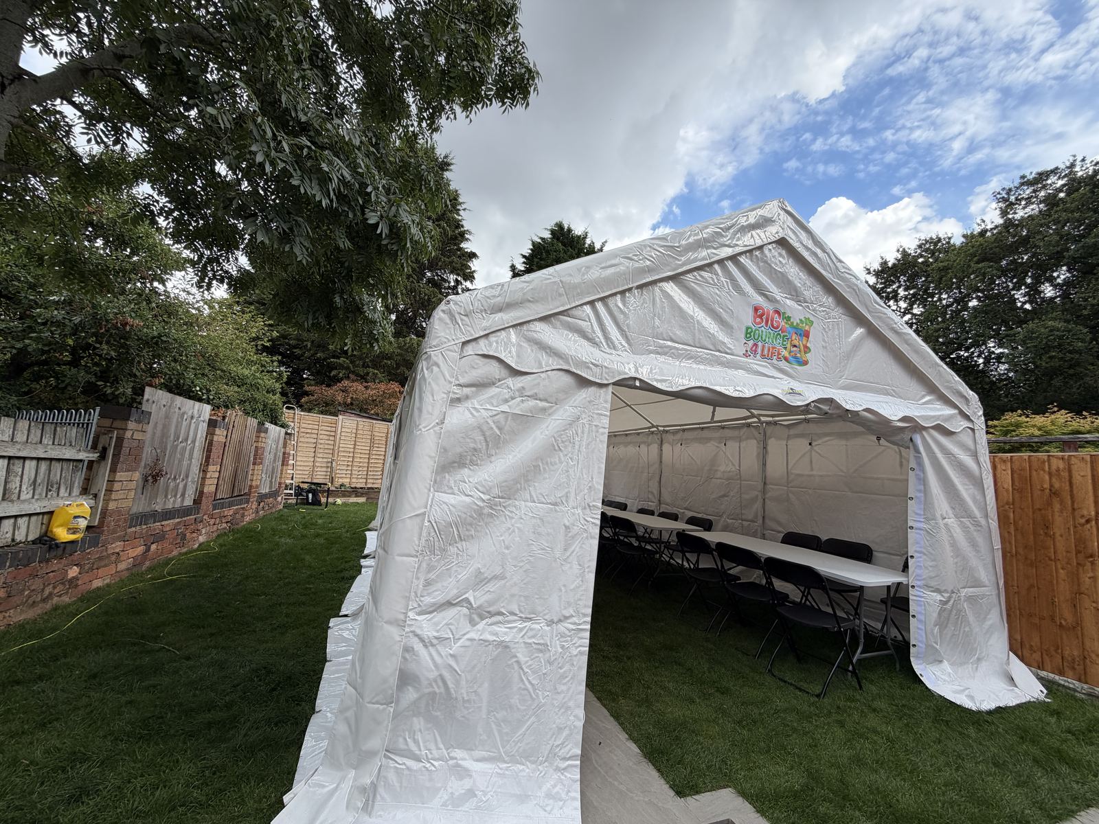 Side view of the marquee on a lawn, with chairs and tables visible through the doorway