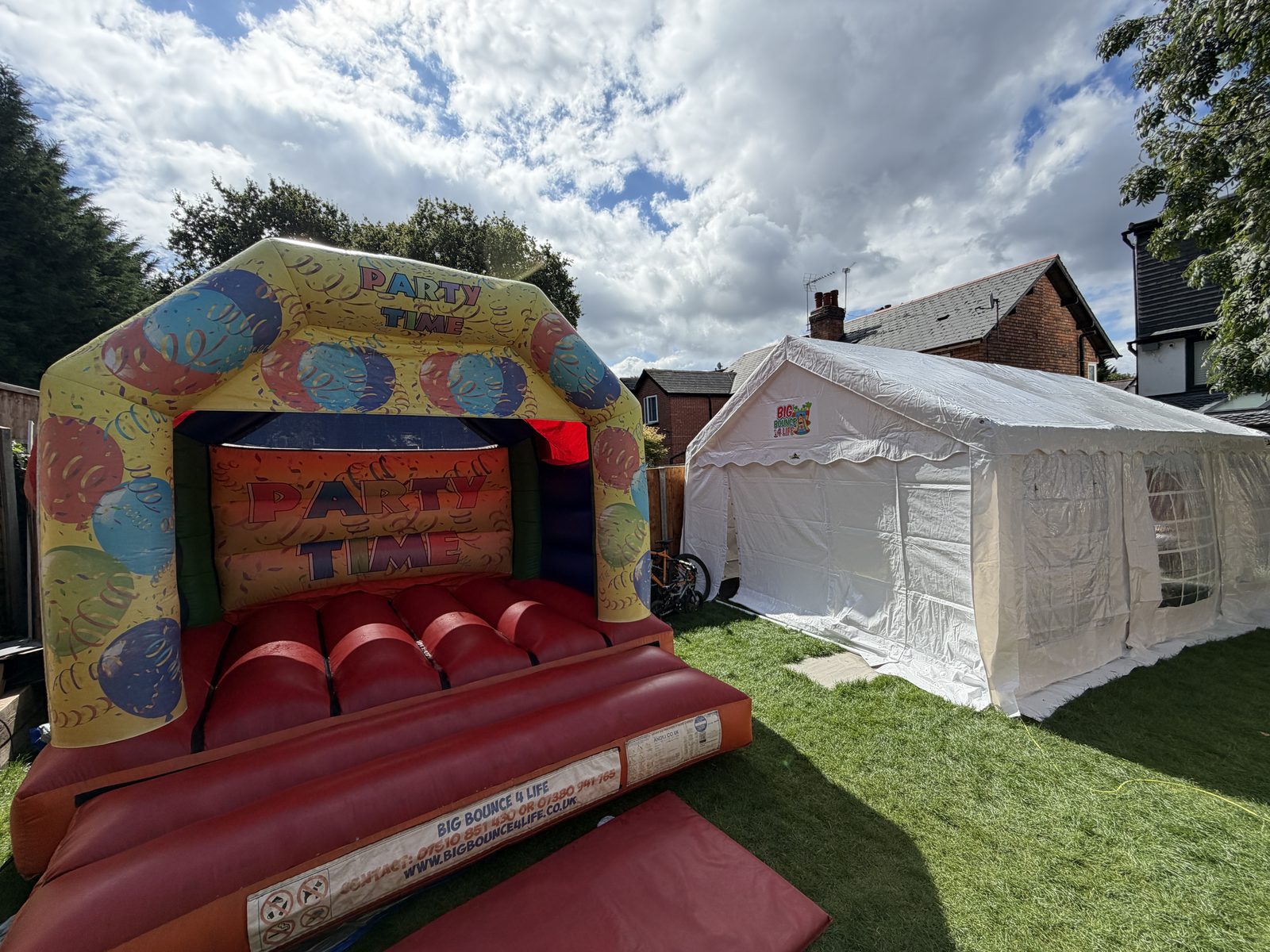 Bouncy castle in front of a marquee on a lawn, the castle package for Longbridge